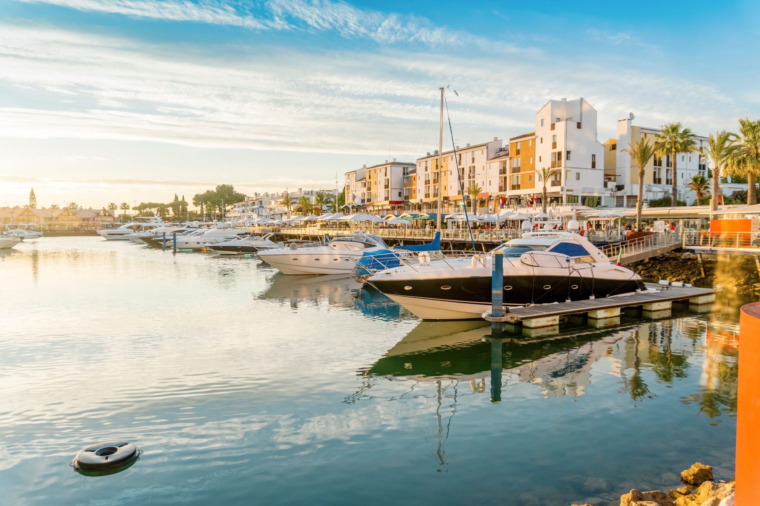 Faro's lively marina, filled with boats and overlooking the Ria Formosa, with restaurants and cafes in the foreground.
