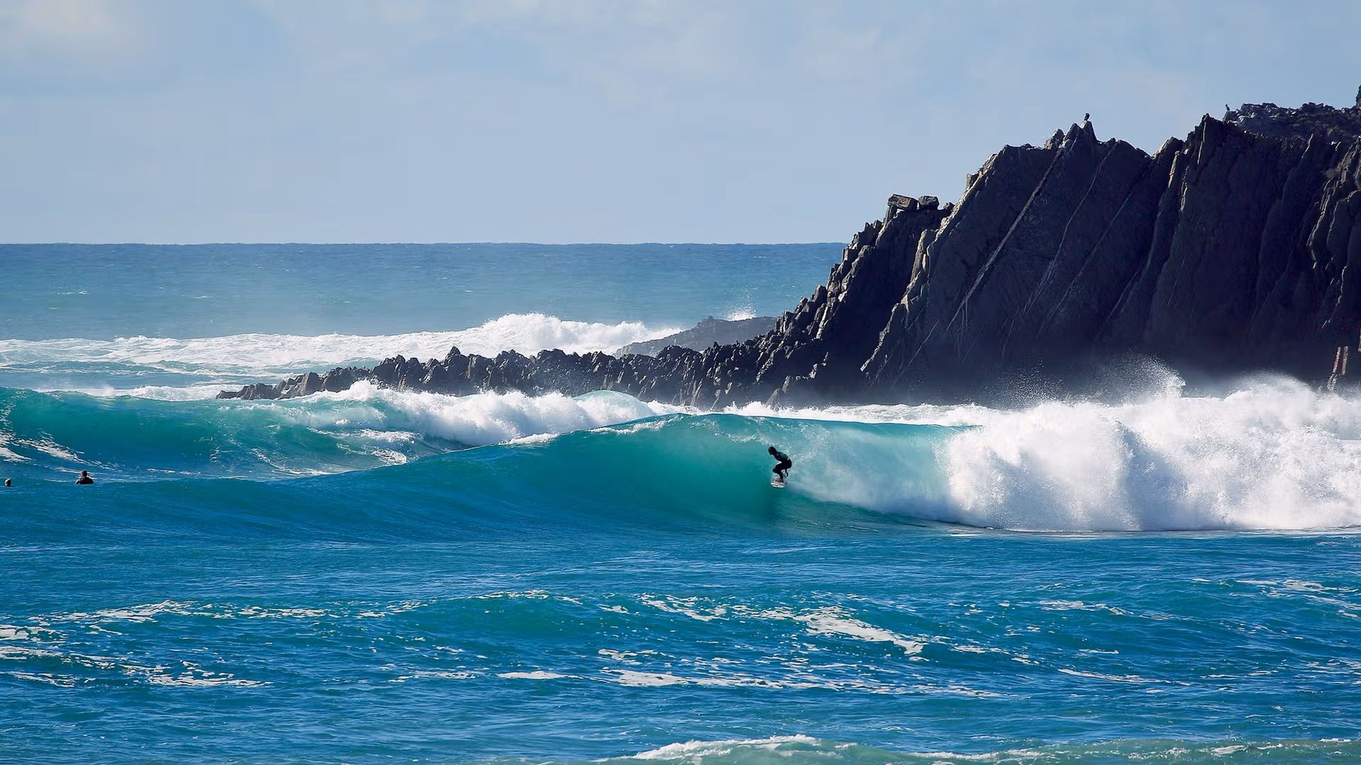 Surfers riding the waves at Sagres in the Algarve